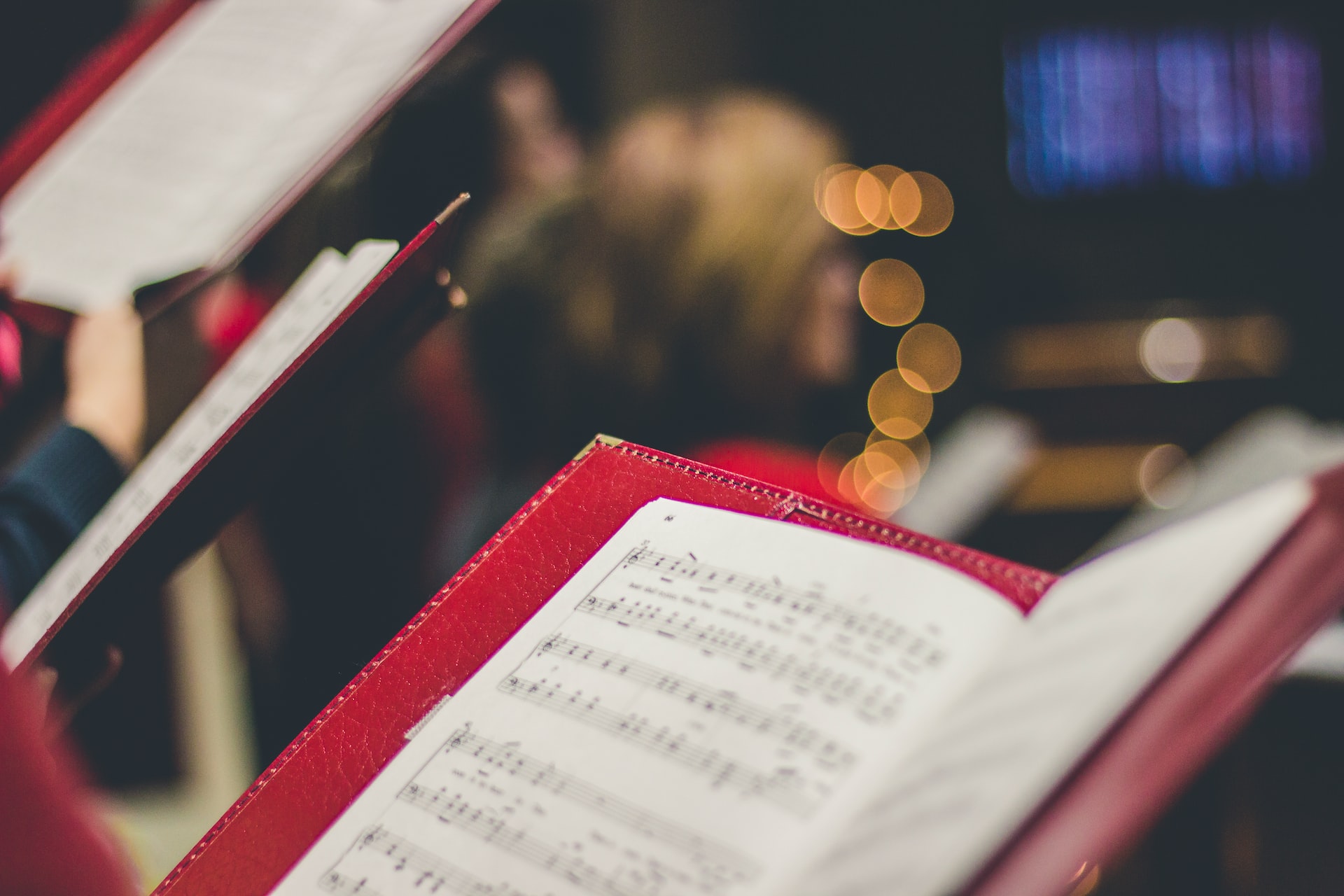 An image of a singer holding sheet music standing amongst a choir.